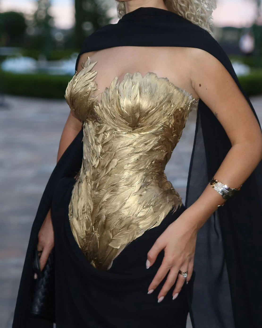 Siyah ve altın rengi couture elbisenin kalp yakalı korse üstünü şekillendiren metalik altın renkli gerçek tüylerin yakın çekimi