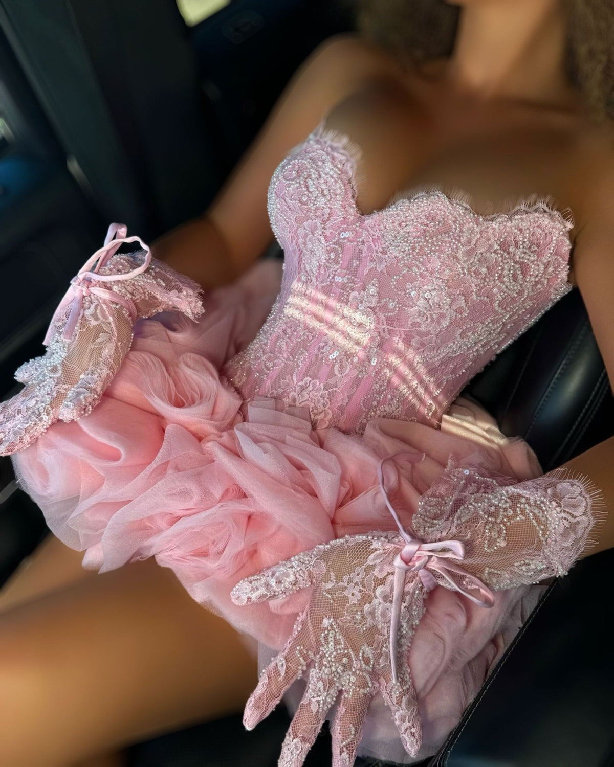 Blush pink lace corset mini dress with layered tulle skirt and crystal gloves, angled view