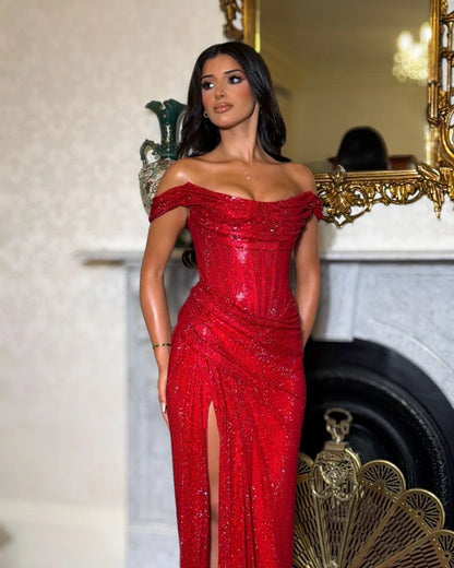 Red glitter evening dress showing structured corset bodice, draped off-shoulder neckline and gathered high-slit skirt