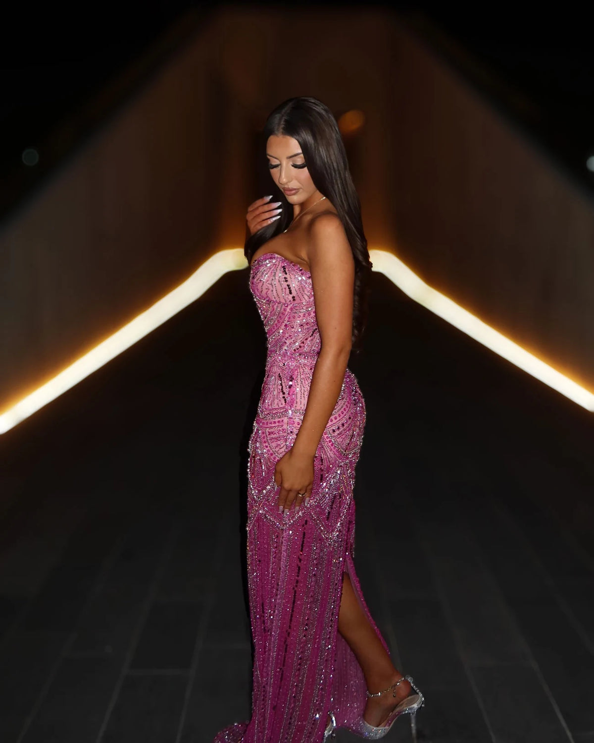 Side view of rose pink strapless crystal corset gown showing fitted silhouette and high side slit