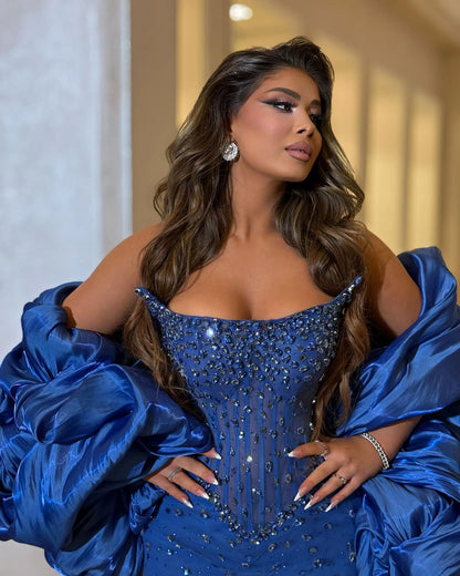 Portrait of royal blue crystal evening gown with sculpted neckline and voluminous draped satin shoulder wrap